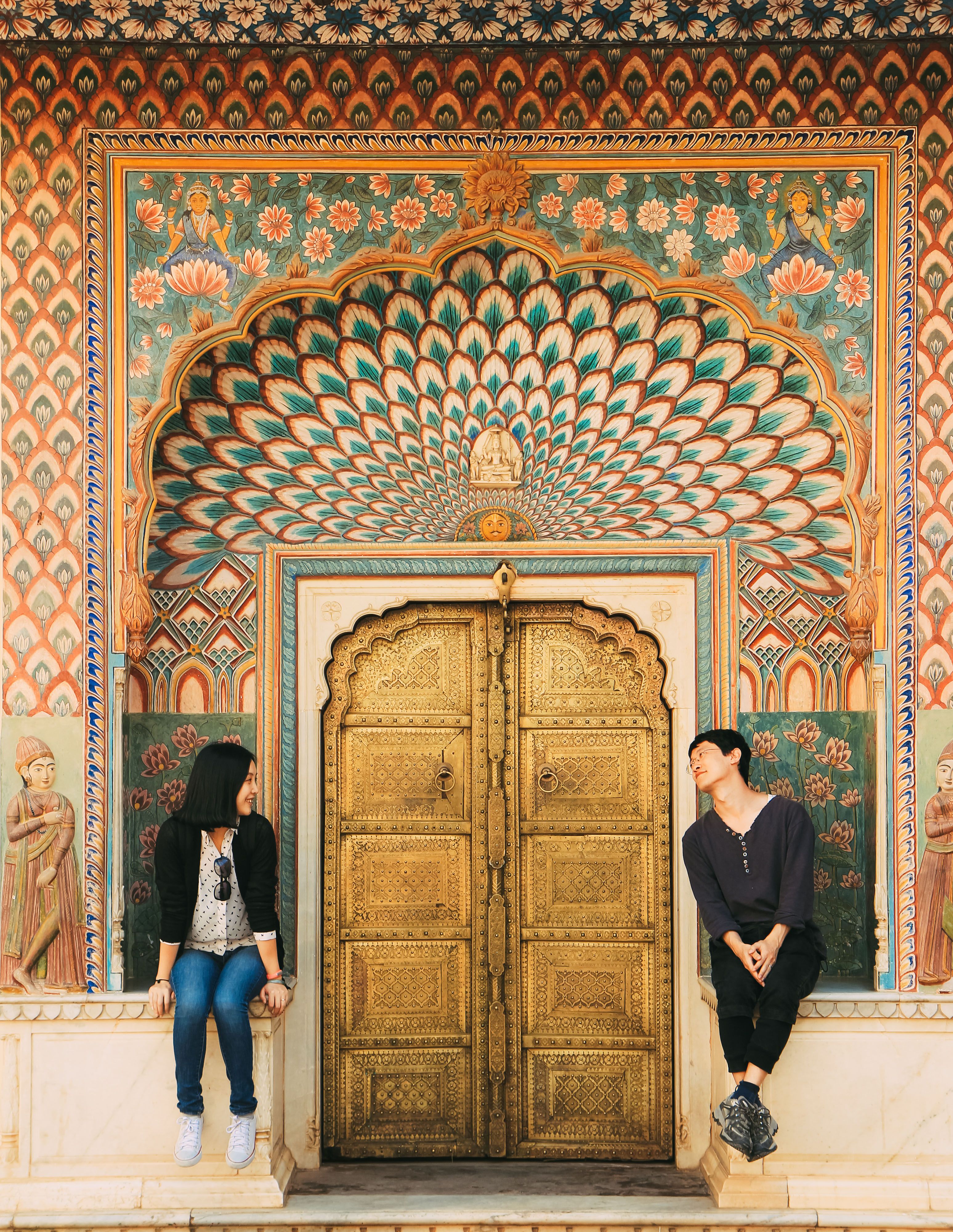 Two founders of LuxAuraStays standing in the arched doorway of a restored Jaipur haveli, dressed in understated traditional attire, natural warm light