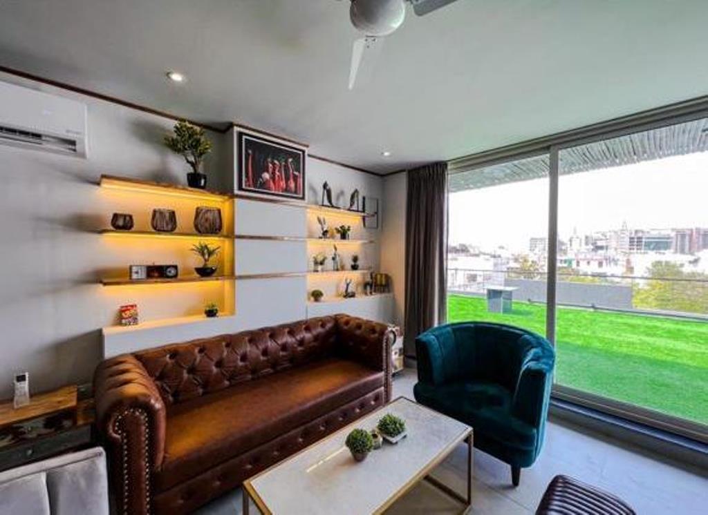 A living room with a brown couch and a chair, a table with a plant on it, and a large window