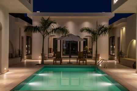 Large pool with white umbrella and lounge chairs, house in the background