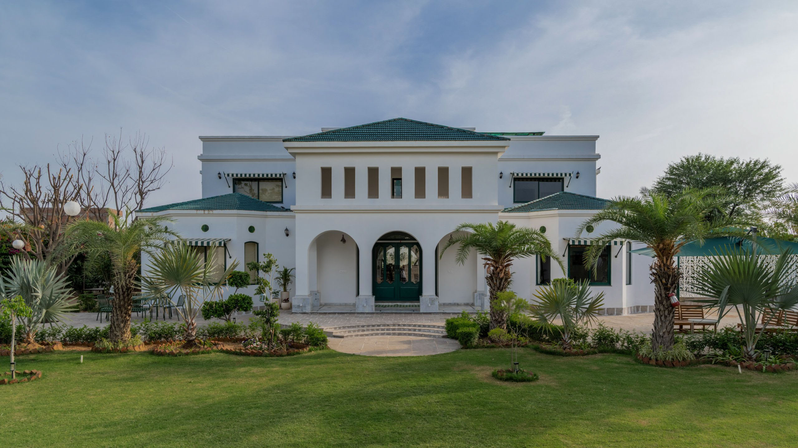 Spacious sunlit apartment living room in Jaipur with comfortable seating, warm interiors, and a large private balcony overlooking gardens, ideal for families
